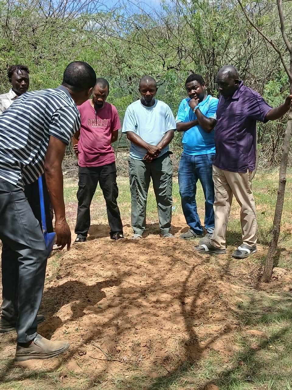GHEA team members gathered around freshly prepared soil during a farming activity in Dadaab